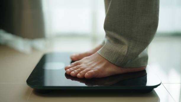 Bare feet stepping onto a weigh scale.